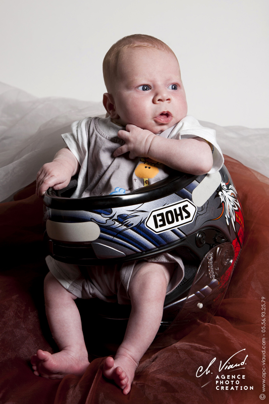 Séance photo originale d'un bébé dans le casque de moto de son papa