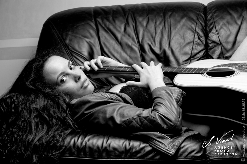 Portrait serré d'une femme allongée dans un canapé avec sa guitare