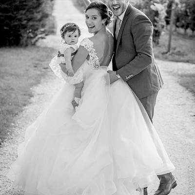 Reportage mariage - Photo sympathique des mariés avec leur fille pendant qu'ils marchent